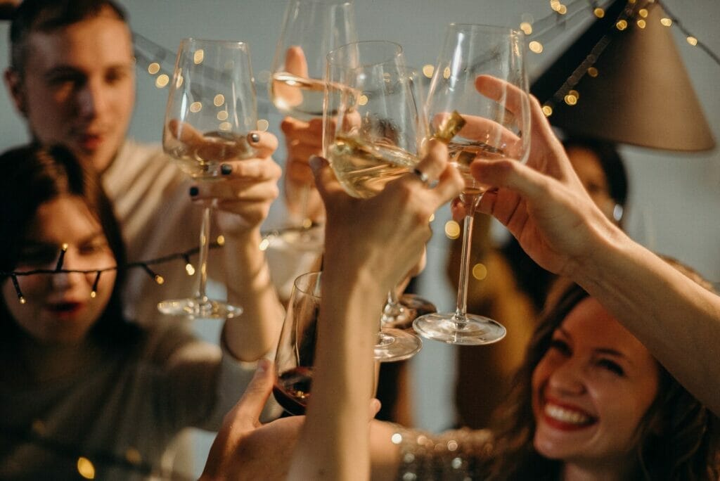 A completely satisfied collection of young women and boys elevating their wine glasses in a toast, celebrating and pronouncing 'Cheers to Life' with smiles on their faces. cheers to life quotes for instagram
