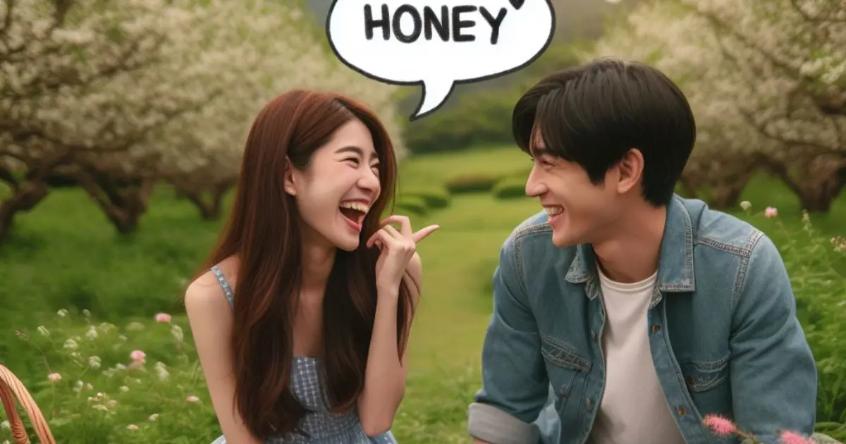A couple enjoys a picnic in a lush meadow surrounded by blooming flowers. The woman affectionately calls her boyfriend "Honey," prompting thoughts on "what does it mean when a girl calls you honey.